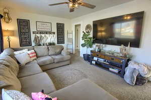 Carpeted living room with ceiling fan