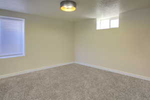 Carpeted spare room featuring a textured ceiling