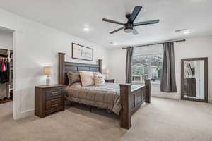 Bedroom with ceiling fan, a spacious closet, a closet, and light carpet