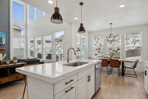 Kitchen featuring pendant lighting, sink, a kitchen island with sink, plenty of natural light, and light wood-type flooring