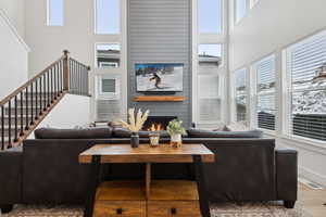 Living room with a towering ceiling, wood-type flooring, a large fireplace, and a healthy amount of sunlight