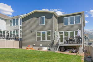 Back of house with central AC, a deck, and a lawn