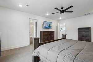 Carpeted bedroom featuring ceiling fan and ensuite bath