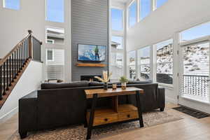 Living room with a high ceiling, a large fireplace, and light hardwood / wood-style floors