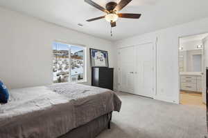 Carpeted bedroom featuring a closet, ceiling fan, and ensuite bathroom