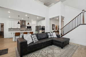 Living room with sink, light hardwood / wood-style flooring, and a high ceiling