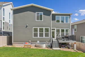 Back of property with a wooden deck and a lawn