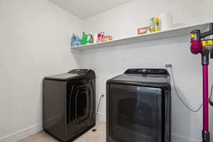 Clothes washing area with light tile patterned flooring and washing machine and clothes dryer