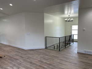 Unfurnished room featuring wood-type flooring, a textured ceiling, and an inviting chandelier