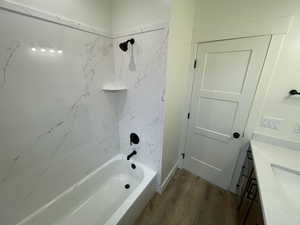 Bathroom featuring tiled shower / bath combo, wood-type flooring, and vanity