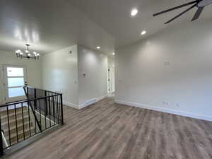 Empty room with ceiling fan with notable chandelier and hardwood / wood-style floors