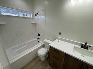 Full bathroom featuring tiled shower / bath combo, vanity, hardwood / wood-style flooring, and toilet