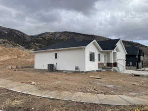 View of side of home with a garage, a mountain view, and central AC unit