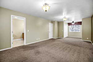 Unfurnished room with ceiling fan, light carpet, and a textured ceiling