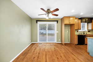 Kitchen with backsplash, ceiling fan, black dishwasher, and light wood-type flooring