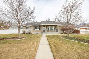 Ranch-style house with covered porch and a front lawn