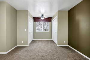 Unfurnished bedroom featuring ceiling fan, carpet, and a textured ceiling