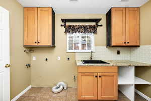 Washroom with light tile patterned flooring, sink, cabinets, hookup for an electric dryer, and hookup for a gas dryer