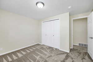 Unfurnished bedroom with a closet, carpet, and a textured ceiling