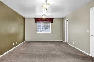 Empty room with carpet and a textured ceiling