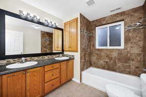 Full bathroom featuring tile patterned flooring, vanity, tiled shower / bath combo, and toilet