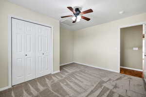 Unfurnished bedroom with light carpet, ceiling fan, and a closet