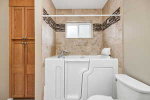 Bathroom featuring a washtub and toilet