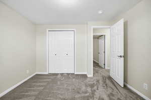 Unfurnished bedroom with a closet, a textured ceiling, and carpet flooring