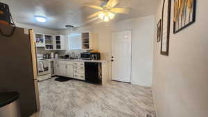 Kitchen featuring sink, stainless steel refrigerator, dishwasher, electric range, and white cabinets