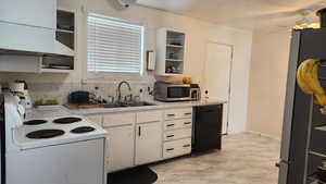 Kitchen with sink, backsplash, white cabinets, ceiling fan, and stainless steel appliances