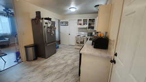 Kitchen with backsplash, white electric range, and stainless steel refrigerator