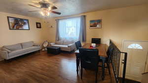 Living room featuring ceiling fan, dark hardwood / wood-style flooring, and a textured ceiling