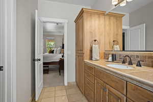 Bathroom featuring vanity, tile patterned flooring, and backsplash