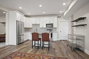 Kitchen featuring a breakfast bar area, white cabinets, and appliances with stainless steel finishes