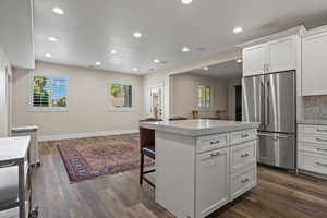 Kitchen featuring white cabinetry, plenty of natural light, high end refrigerator, and a center island