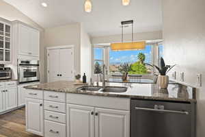 Kitchen with stainless steel appliances, sink, dark stone countertops, and white cabinets