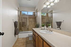 Full bathroom featuring vanity, bath / shower combo with glass door, and toilet