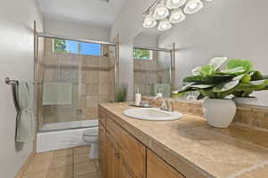 Full bathroom with toilet, tile patterned floors, bath / shower combo with glass door, and vanity