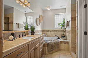 Bathroom featuring vanity, a relaxing tiled tub, and tile patterned floors