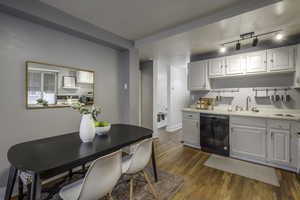 Kitchen featuring white cabinets, sink, dishwasher, and light wood-type flooring