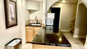 second Kitchen with sink, dark stone countertops, backsplash, and light tile patterned floors