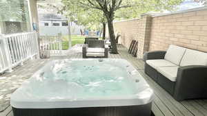 Wooden deck featuring a hot tub and an outdoor hangout area