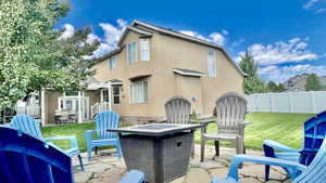 Rear view of house featuring a lawn, a patio, and an outdoor fire pit