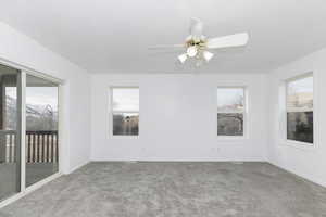 Empty room featuring ceiling fan, plenty of natural light, carpet floors, and a textured ceiling