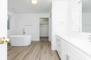 Bathroom with a washtub, vanity, and hardwood / wood-style flooring