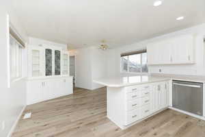 Kitchen with white cabinetry, dishwasher, kitchen peninsula, and light wood-type flooring