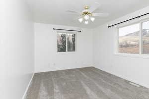 Carpeted spare room featuring a mountain view and ceiling fan