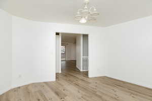 Empty room with an inviting chandelier and light hardwood / wood-style floors