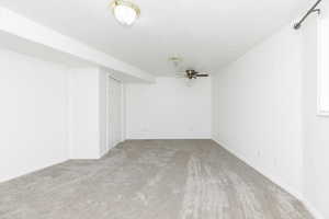 Basement with ceiling fan and carpet