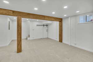 Basement featuring a barn door and light carpet